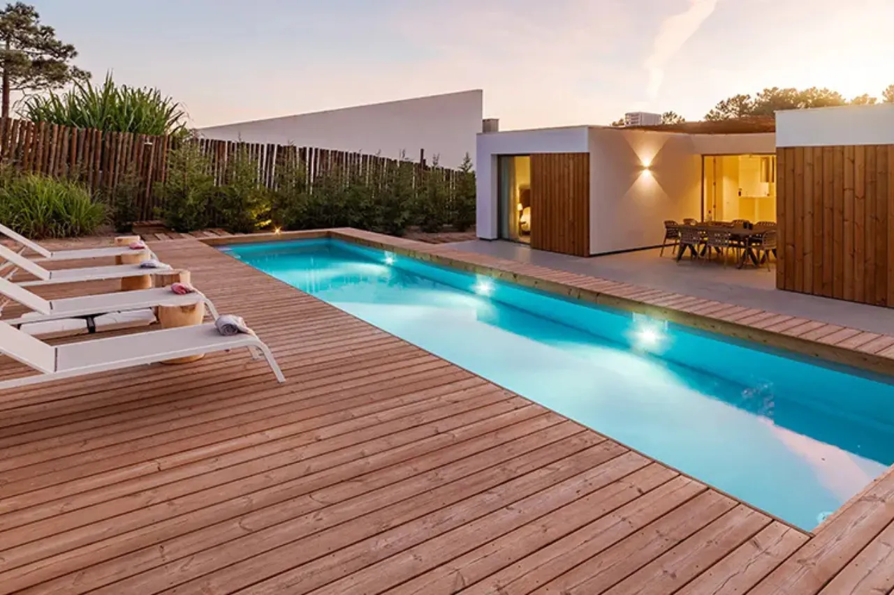 Warm cedar pool deck with loungers and integrated deck lighting at sunset