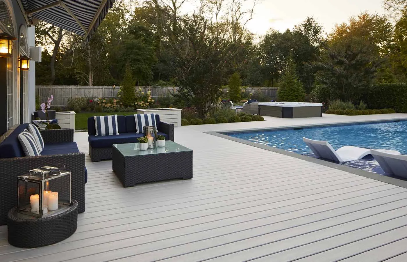 Gray composite pool deck with lounge seating and a spa at dusk behind a Tampa home